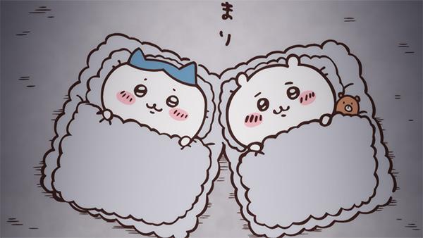 ふかふかの布団にくるまって、ハチワレとちいかわが並んで横になっている。ちいかわの枕もとには小さな茶色いくまのようなものがある、アニメ「ちいかわ」第24話「おうち／お泊まり」の場面