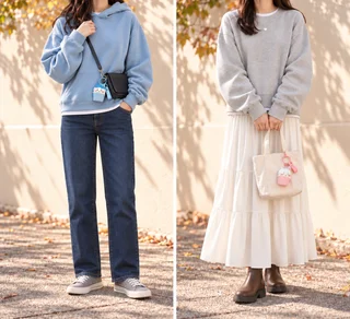 腰骨くらいの丈の水色パーカーとストレートデニム、杢グレーのトレーナーとアイボリーのティアードスカートに、小さなキャラクターストラップを添えた秋冬コーデ(AI生成)